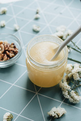 Walnuts, honey and white flowers on table