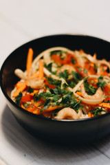 Chopsticks and delicious salad with vegetables shrimps in black plate, Asian cuisine