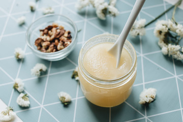 Walnuts, honey and white flowers on table
