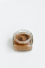Chocolate cream in small jar on white background