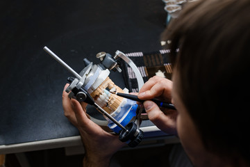 Dental technician working with articulator in dental laboratory