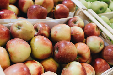 Pile of fresh ripe red apples in boxes at market