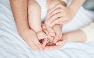 Fototapeta na wymiar Children's feet in the hands of parents