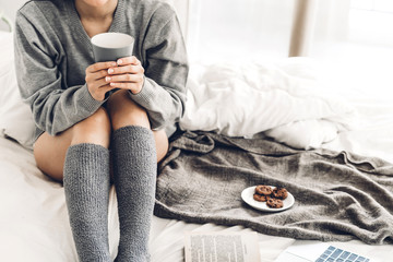 Young woman relaxing and drinking cup of hot coffee or tea on a cold winter day in the bedroom.Winter and cold weather concept