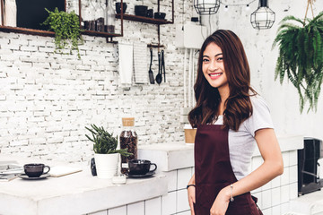 Portrait of woman barista small business owner smiling behind the counter bar in a cafe