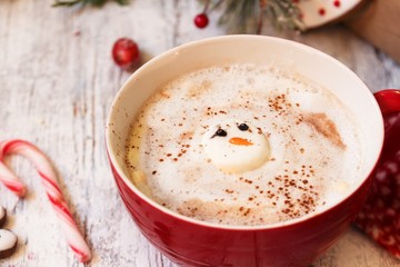 Marshmallow sonwman in a red mug with hotchocolate on festive X-mas background