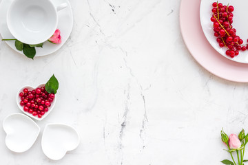 Simple color table setting for celebration with roses, pink plates and wineberry on white table background top view mock up