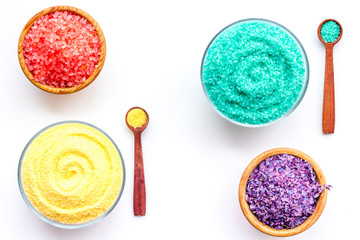 Spa salt background. Colorful spa salt in bowls on white background top view. Yellow, turquoise, pink, purple spa salt