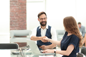 businessman and businesswoman shaking hands over the Desk