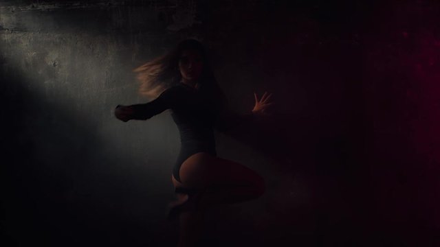 Enchanting girl is dancing sexually alone in dark hall. She is leaning on a wall and moving hips and hands, lowering along wall. Shoot with RED RAVEN camera. 