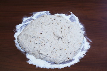 Natural yeast rye dough according to the original old homemade recipe with white flax, sesame and sunflower seeds on wooden tabletop.