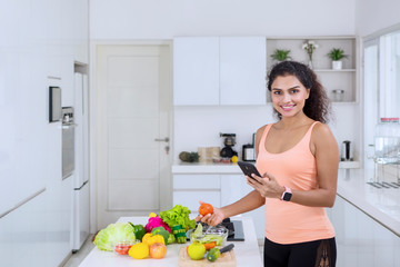 Woman making salad while holding cellphone
