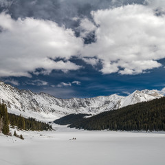 Frozen lake with ice fishermen surrounded by mountains