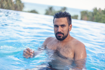 Young attractive sexy Hispanic male, mixed race with beard in the pool, leisure and travel in warm countries