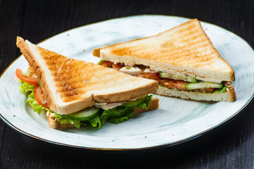 Sandwich with ham, cheese, tomatoes, lettuce, and toasted bread. Above view isolated on dark background