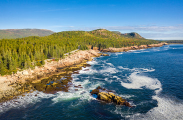 Aerial view of Acadia shore in Maine on a sunny morning with waves crashing on rocky cliffs - Powered by Adobe