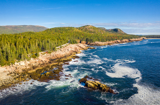 Aerial view of Acadia shore in Maine on a sunny morning with waves crashing on rocky cliffs