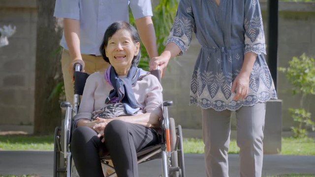 Son and daughter in law looking after elderly mother in backyard