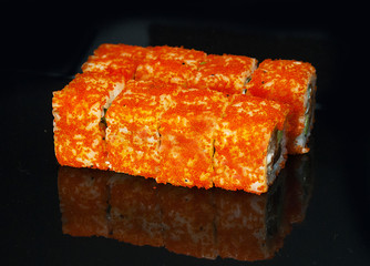 Japanese rolls are served on a black background with reflection