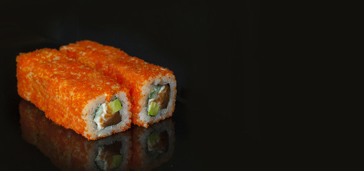 Japanese rolls are served on a black background with reflection. Free space for text.