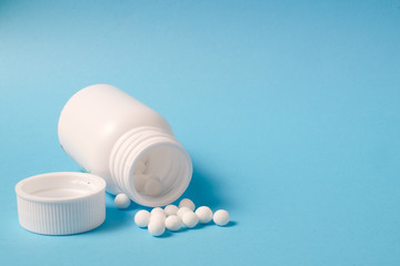 White pills and bottle on blue background