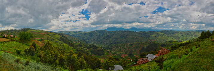 Panoramic Uganda farmland and buildings with Muhavura Volcano in far distance