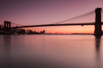 View on Brooklyn Bridge from east river at sunset with long exposure