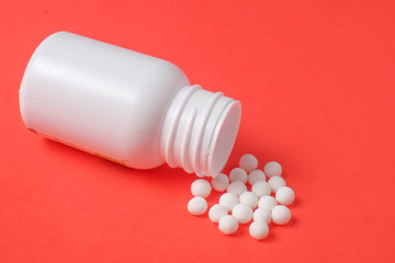 White pills and bottle on red background