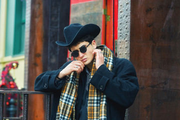 portrait of a stylish man on the street . man in black coat, plaid scarf and hat