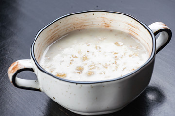 Morning Breakfast, oatmeal on milk with butter in white plate on dark background