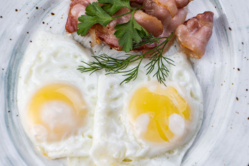 Scrambled eggs and bacon in a white plate on a dark background close-up. Omelet