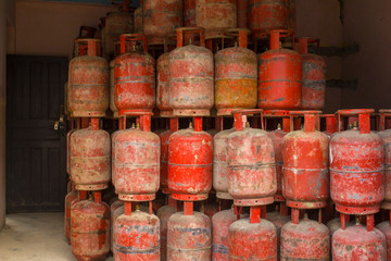 Fototapeta premium a warehouse of old red gas cylinders standing on top of each other. poor state of gas equipment