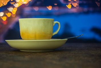 The Cup stands on a saucer with a colorful bokeh.