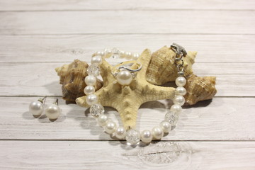 Handmade jewelry made of freshwater pearls and silver. starfish and shells on a light background.