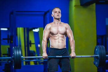 Fototapeta na wymiar Muscular man workout with barbell at gym. Brutal bodybuilder athletic man with perfect abs, shoulders, biceps, triceps and chest. Dead lift barbells workout