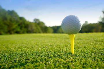 Golf ball on tee in beautiful golf course at sunset background.