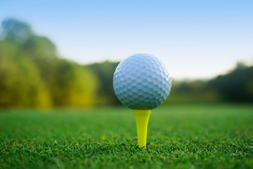 Golf ball on tee in beautiful golf course at sunset background.