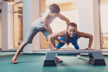Girl does push ups from the bench with a trainer
