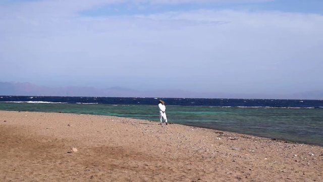 Muslim man walking alone at sandy beach at windy day slow motion shaky footage