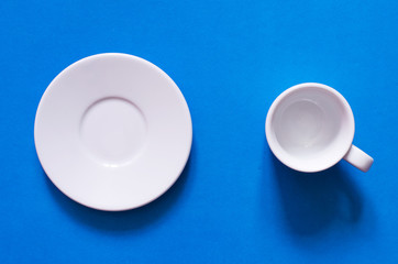 White cup and white plate on the blue background.
