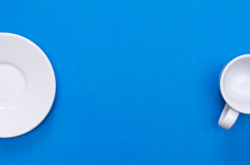 White cup and white plate on the blue background.