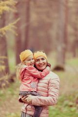 beautiful girl and mother in knitted crown walk in autumn park
