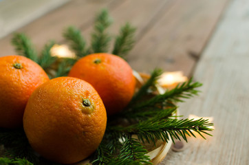 Chritsmas background with tangerines and fir branches and lights. Copy space.