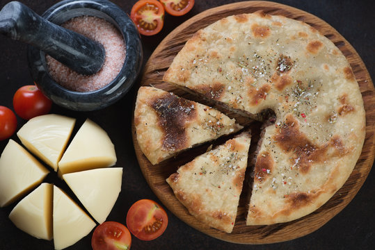 Close-up of sliced ossetian pie, suluguni cheese and tomatoes, view from above