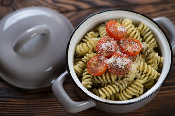 Fusilli with basil pesto sauce and cherry tomatoes in a grey pan, elevated view, closeup