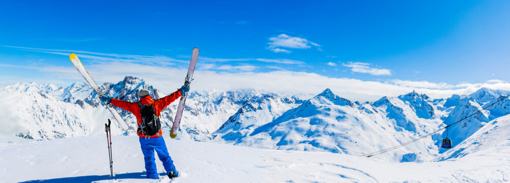 Ski in winter season, mountains and ski touring equipments on the top in sunny day in France, Alps above the clouds.