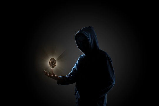 Golden Bitcoin floating above of hacker's hand in dark background. Finance, business, e-commerce or cyber crime concept