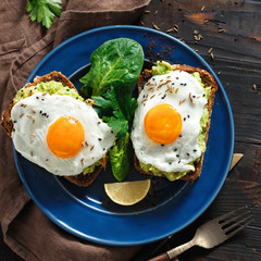 Healthy breakfast avocado toasts fried egg cheerful faces Top view healthy table