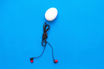 Chicken egg with headphones body is walking on the blue background.