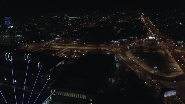 Aerial; drone flight down near the illuminated ferris wheel with night cityscape on background; Chelyabinsk, Russia